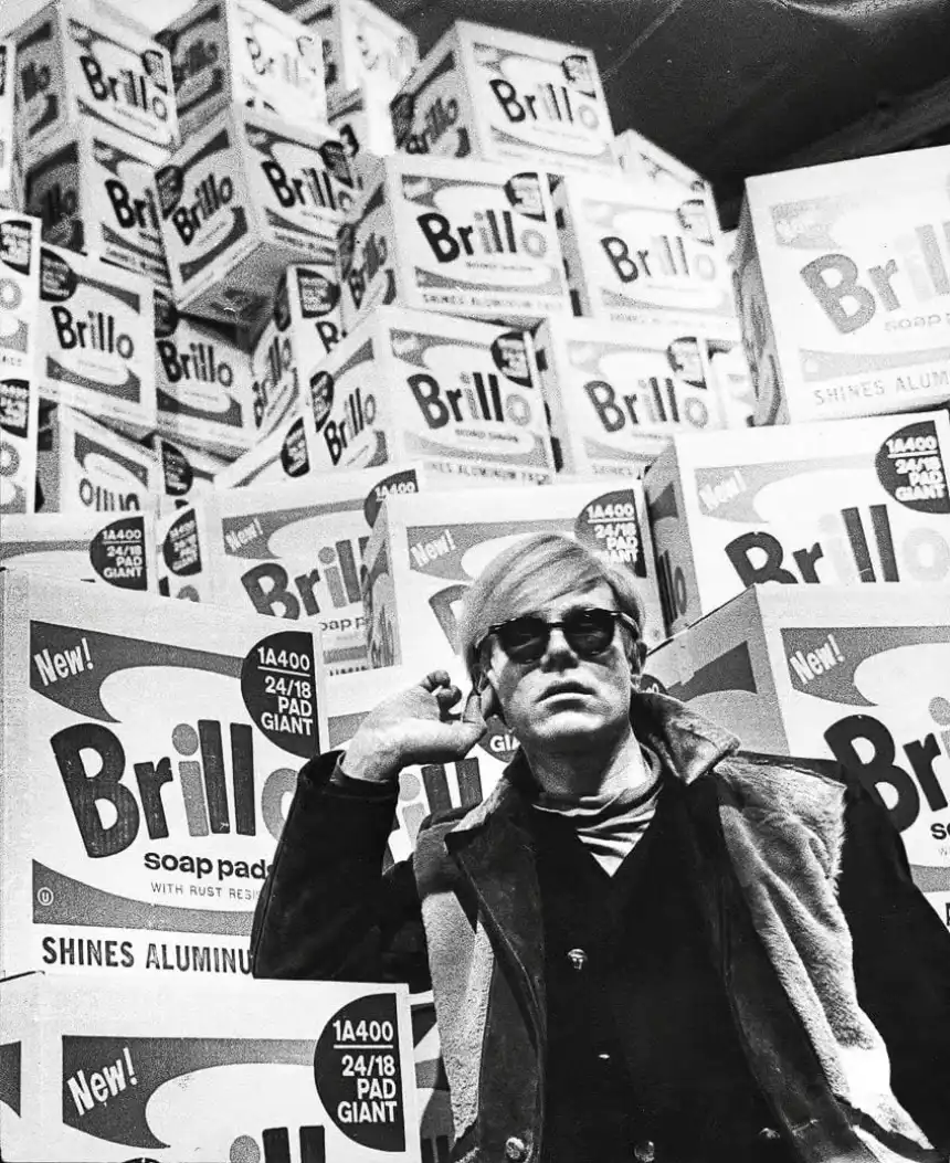 Modernistas populares - Fotografía del artista estadounidense Andy Warhol de pie frente a sus cajas Brillo